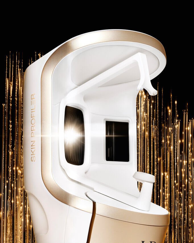 Ein futuristisches weiß-goldenes „Skin Profiler“-Gerat mit leuchtendem Bildschirm, auf schwarzem Hintergrund mit goldenen Leuchtmustern.