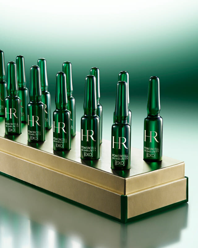 14 grune Powercell Skinmunity EXO-Einzeldosis-Ampullen auf einem edlen goldenen Sockel.