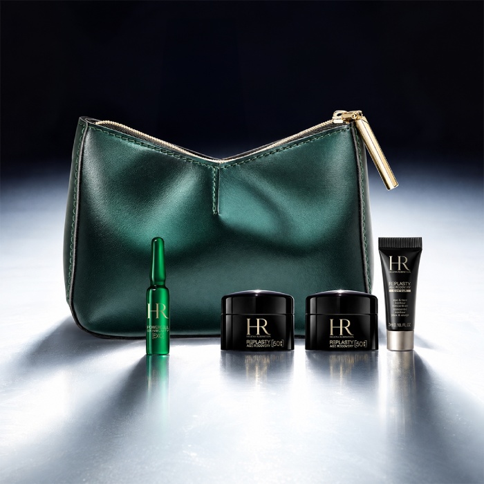 Eine grüne Kosmetiktasche von Helena Rubinstein vor einer hellen Landschaft, umgeben von vier Miniatur-Hautpflegeprodukten: einer Re-Plasty Creme, einem Powercell [EXO] Mini-Serum, einem Powercell Skinmunity Serum und einem Pure Ritual Cleanser.​